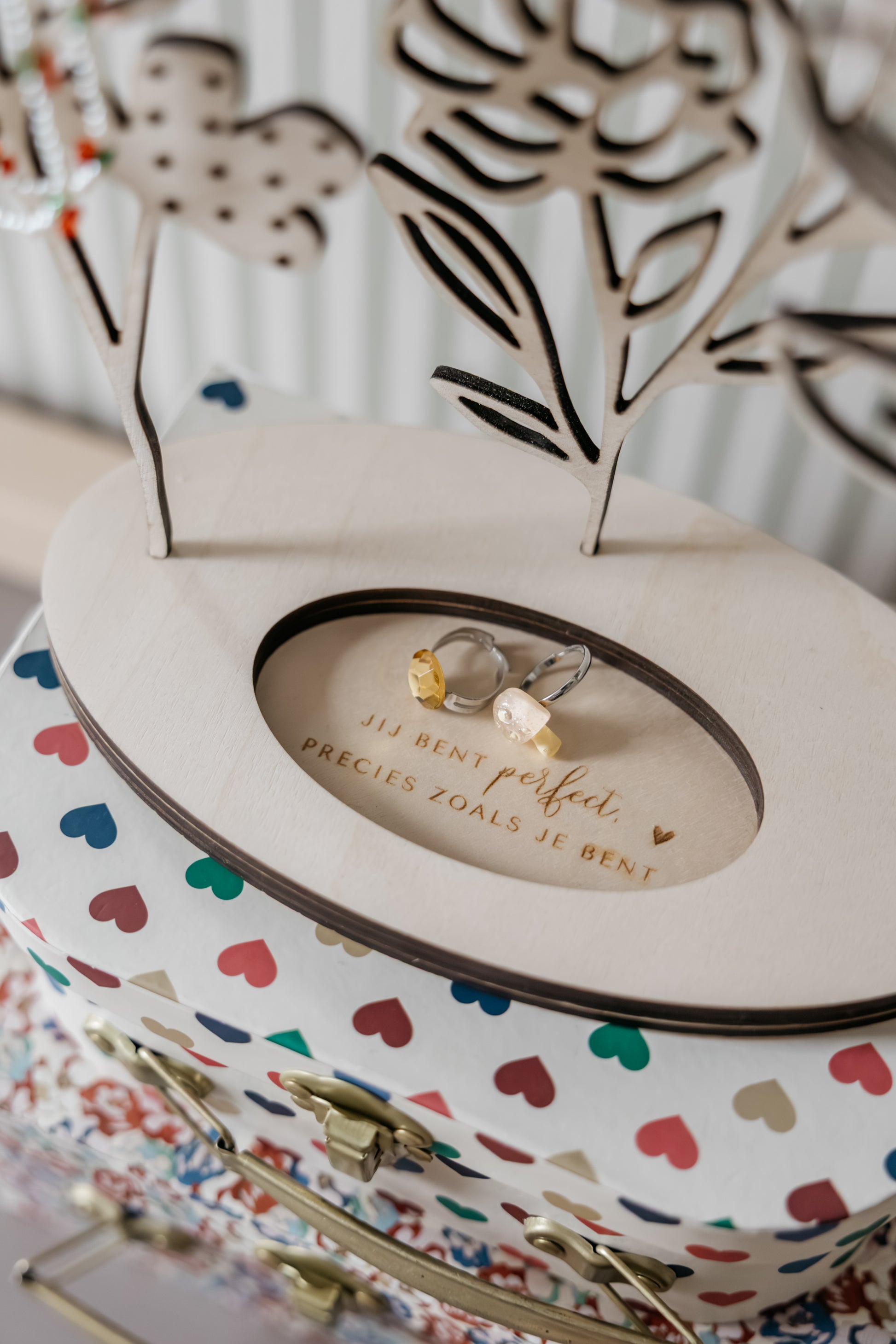 Detail van houten sieradenhouder met bloemen, gegraveerd vak en plek voor ringen en kettingen
