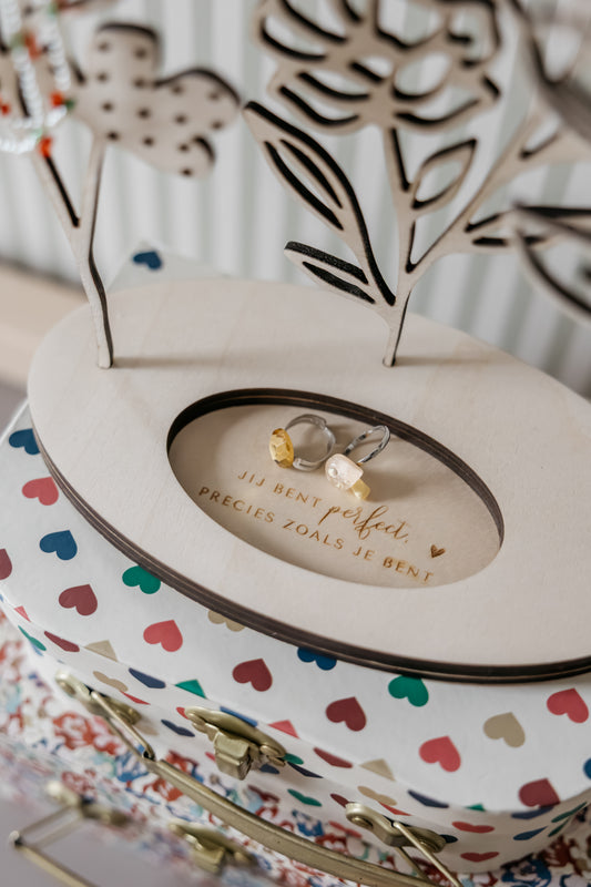 Detail van houten sieradenhouder met bloemen, gegraveerd vak en plek voor ringen en kettingen
